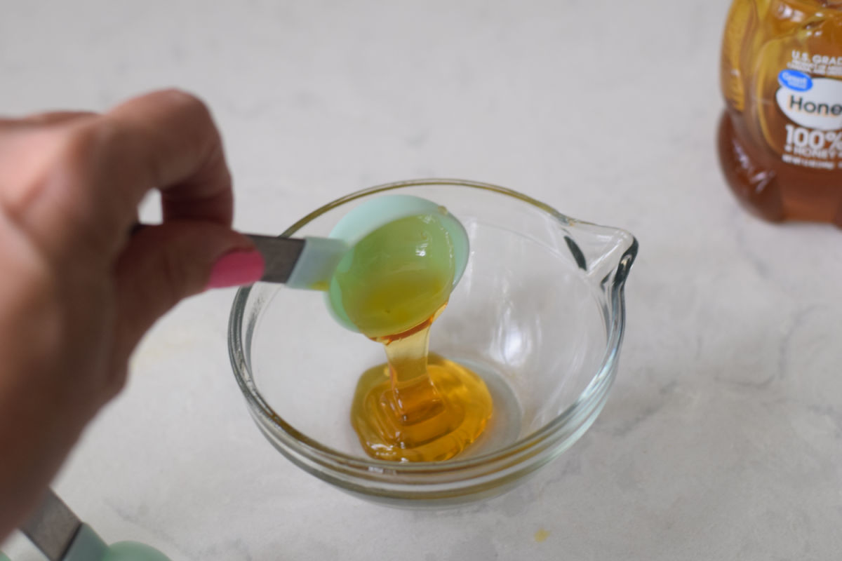 pouring honey from measuring spoon